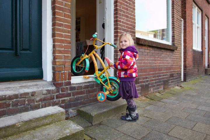 Foto van meisje met fietsje bij voordeur met hoge opstap